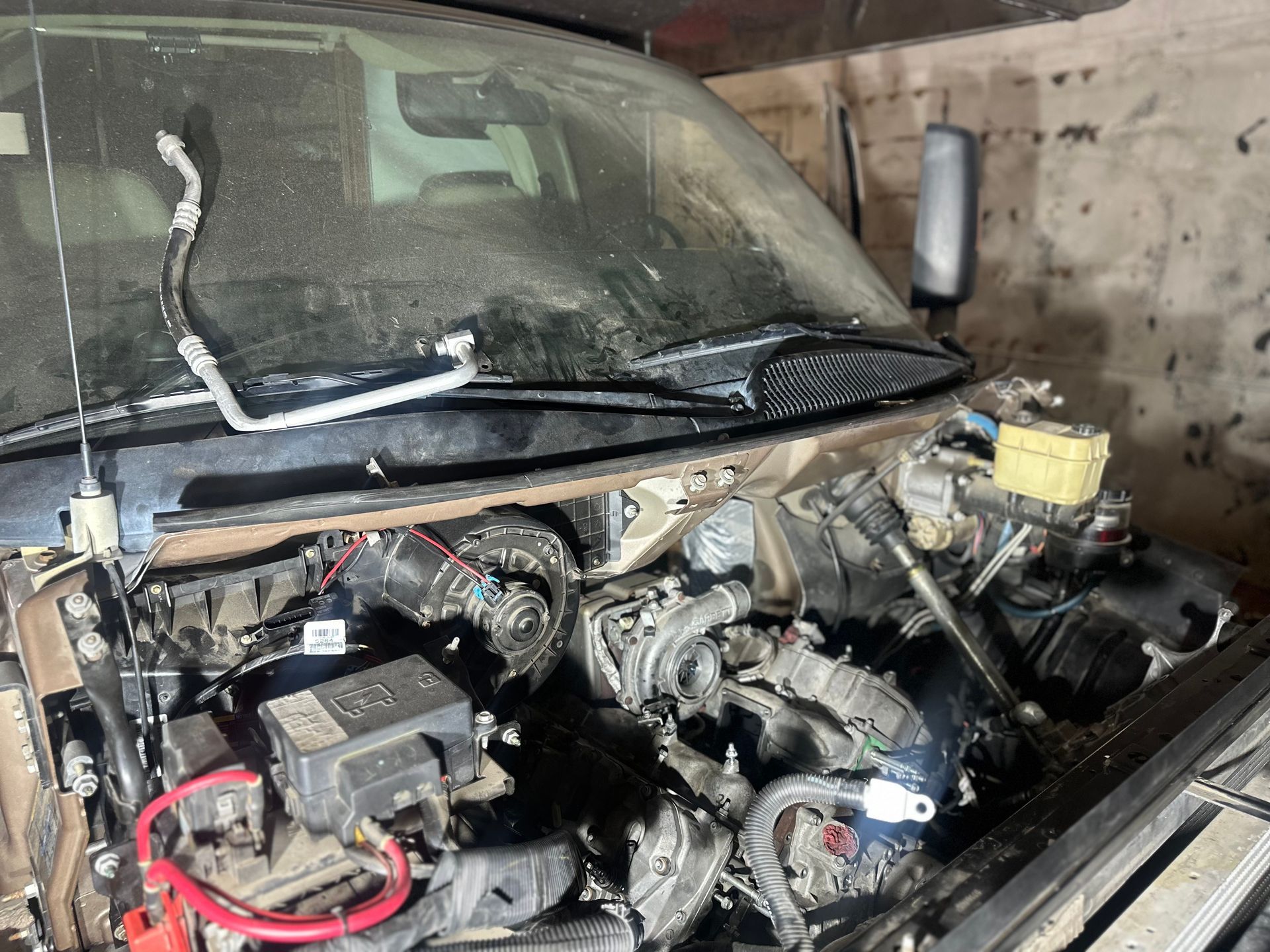 A car with the hood open is sitting in a garage.