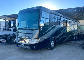 Dark blue and silver RV parked outside in a sunny area.