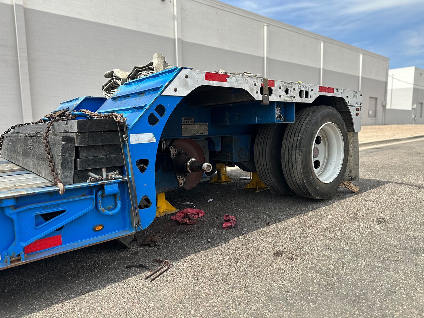 A blue trailer is parked on the side of the road next to a building.