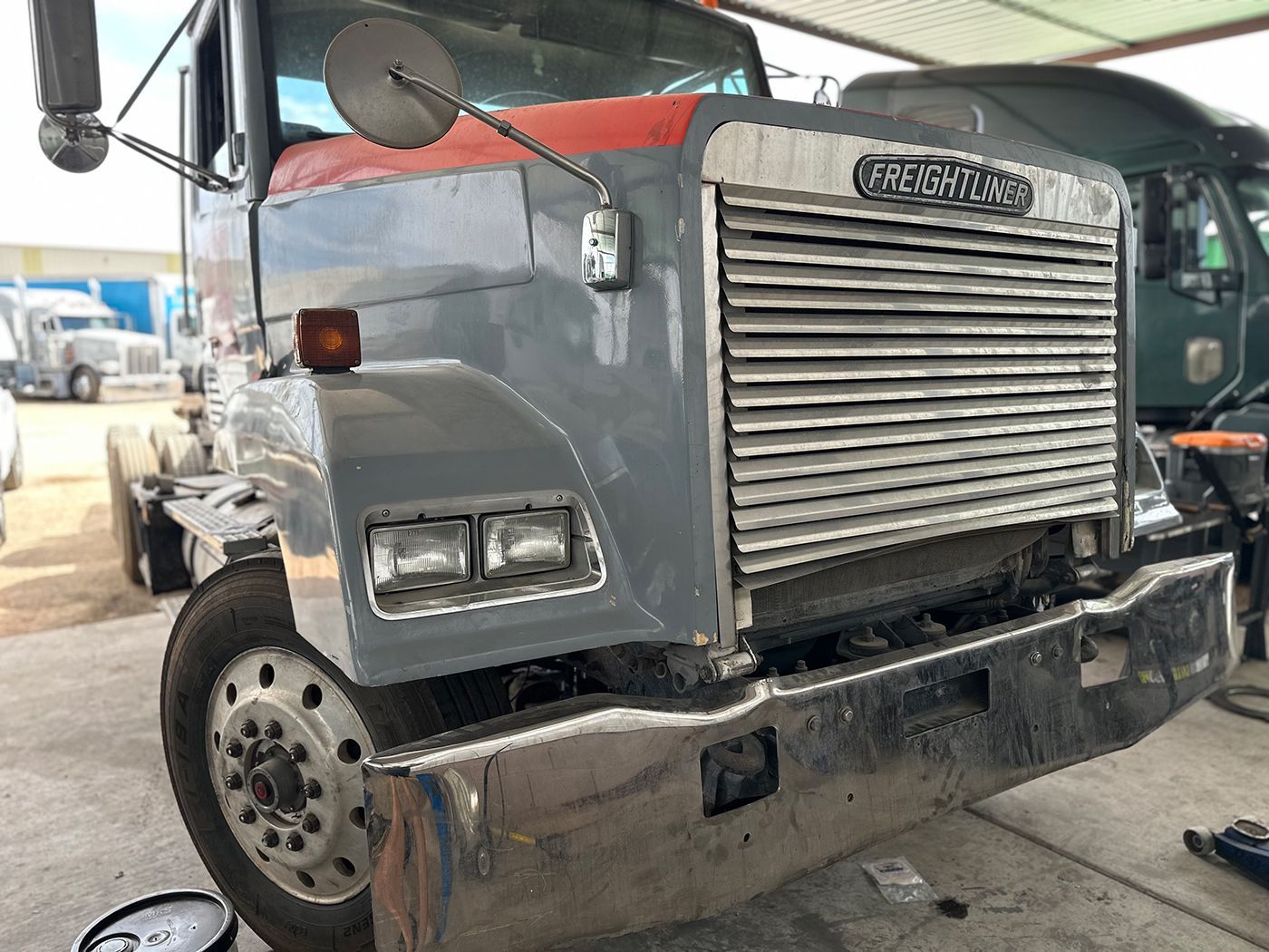 A semi truck is sitting on the ground in a parking lot.
