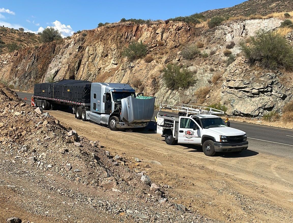 A truck is being repaired in a garage with the hood open.