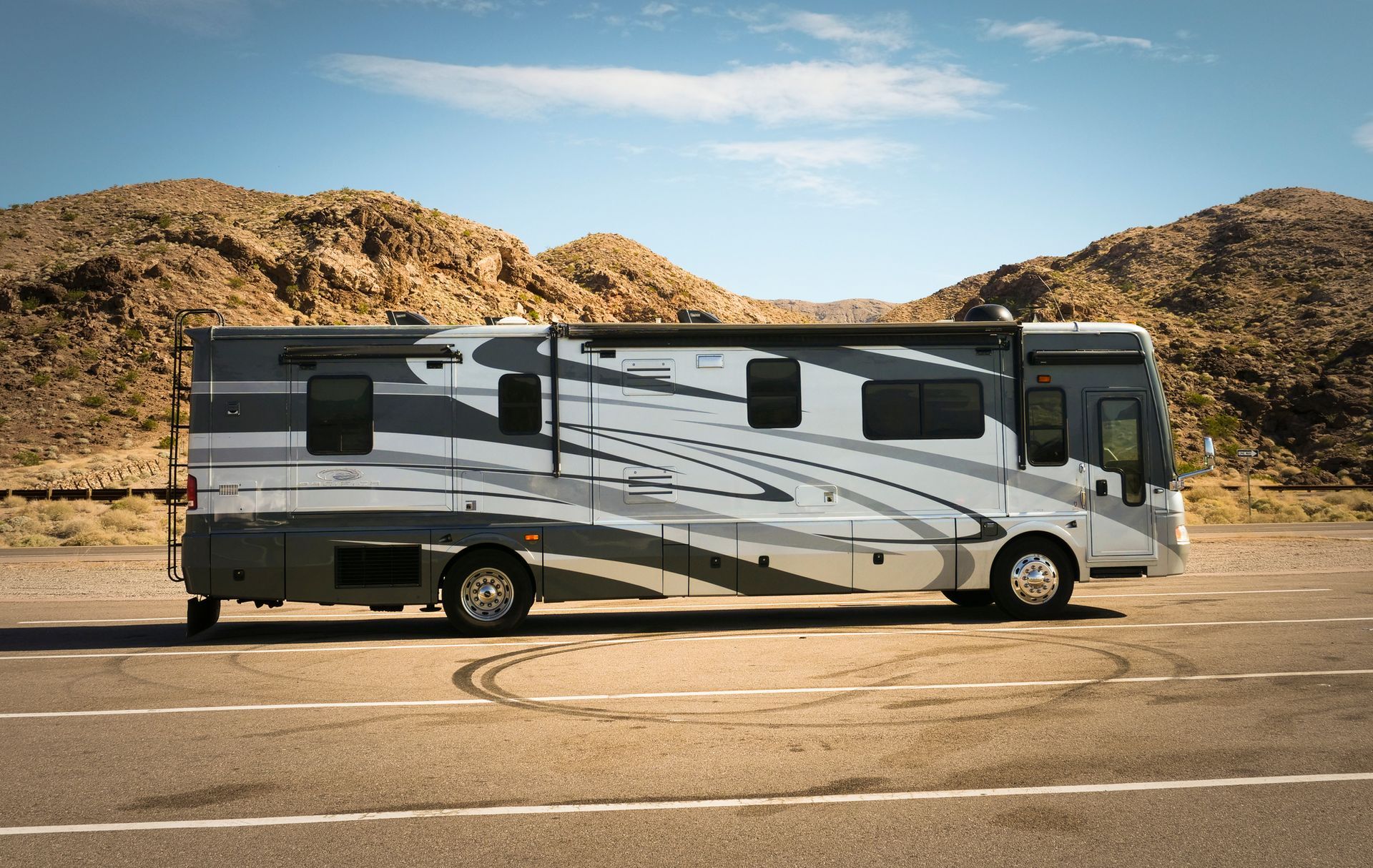 A large rv is parked on the side of the road in the desert.