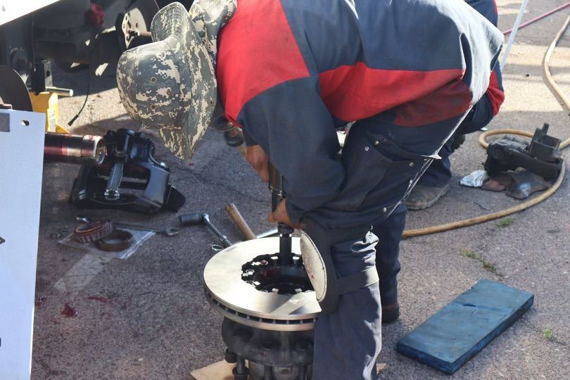 A man wearing a hat is working on a brake disc