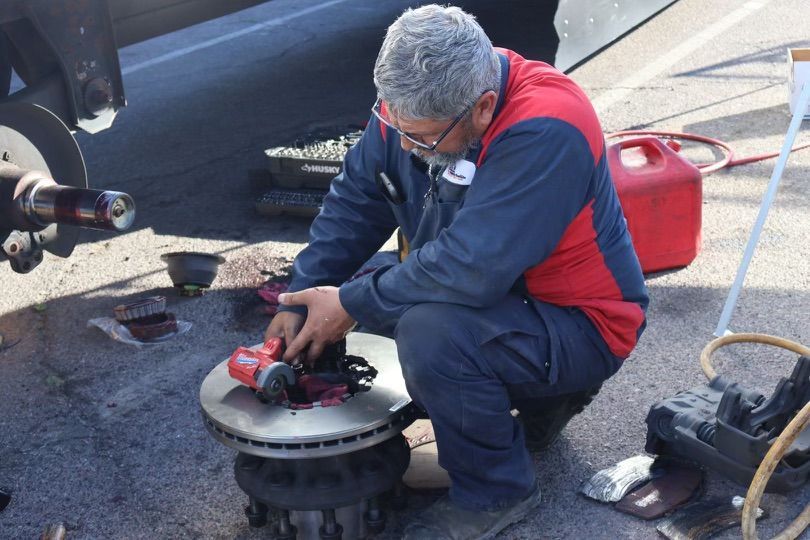 A man is working on a brake disc with a grinder.