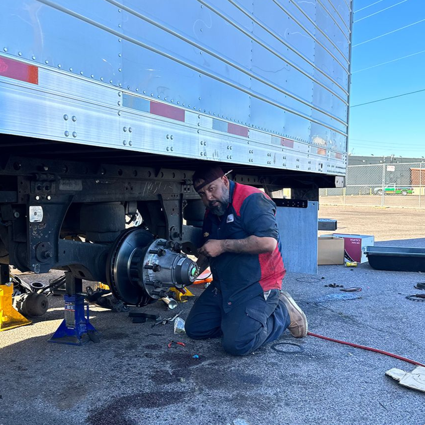 a man is kneeling down working on a truck wheel .