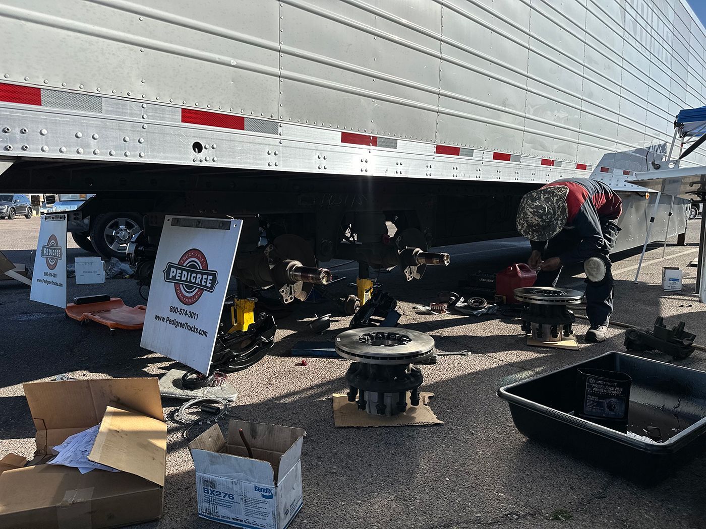 A man is working on a semi truck on the side of the road.
