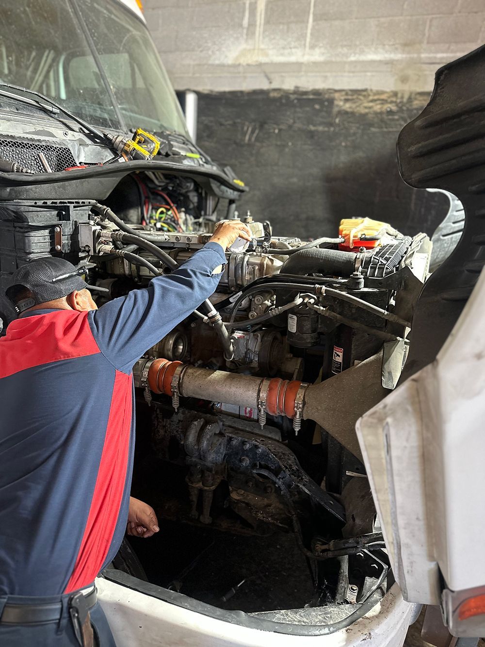A man is working on the engine of a truck.