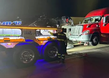 A fireman is standing next to a tow truck.
