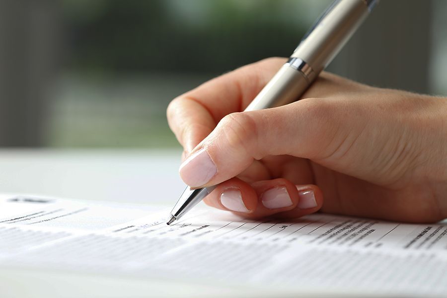 A man is writing on a piece of paper with a pen.