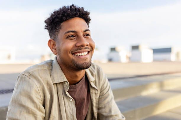 A young man is smiling while sitting on a bench.