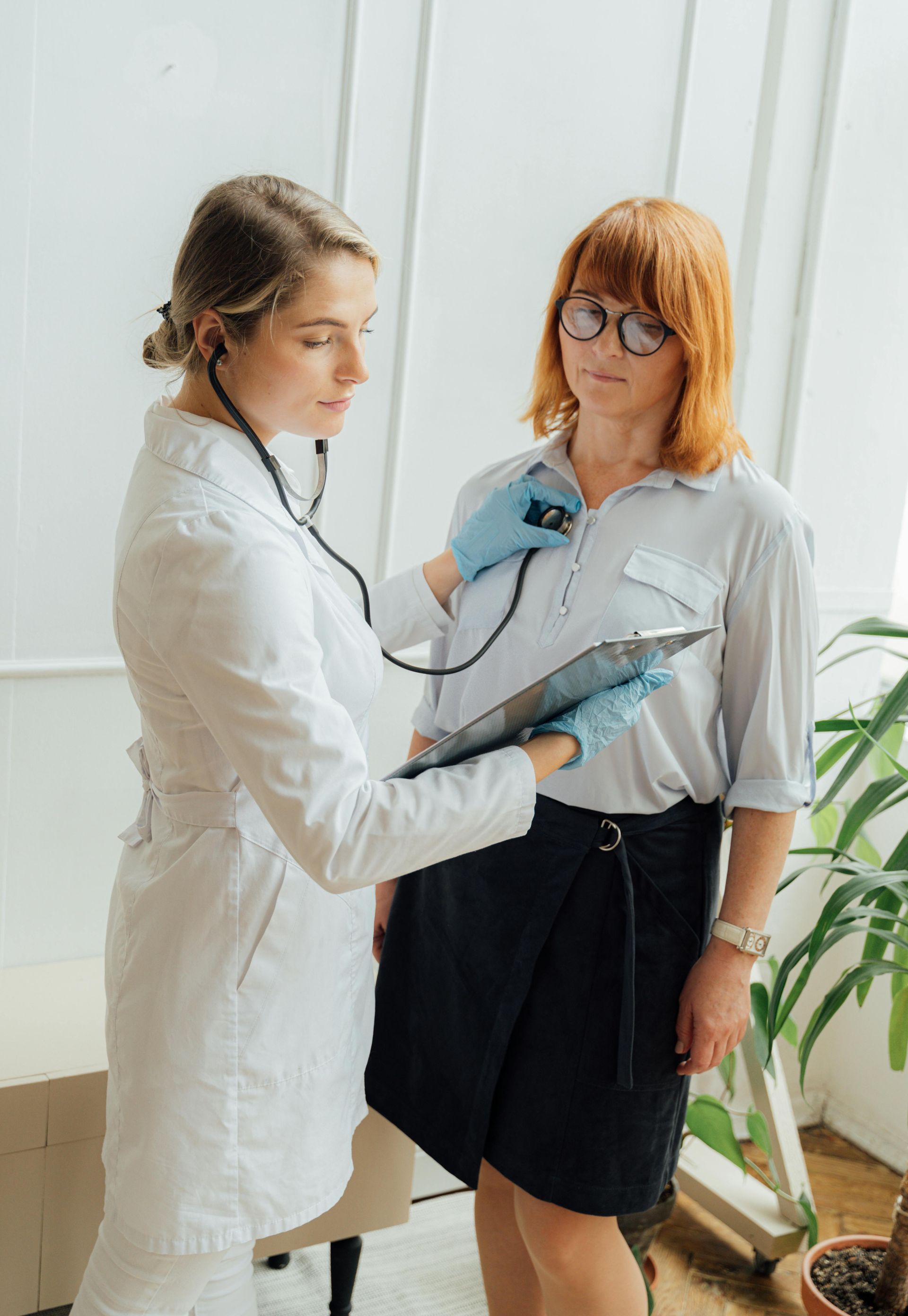A doctor is listening to a patient 's heartbeat with a stethoscope.