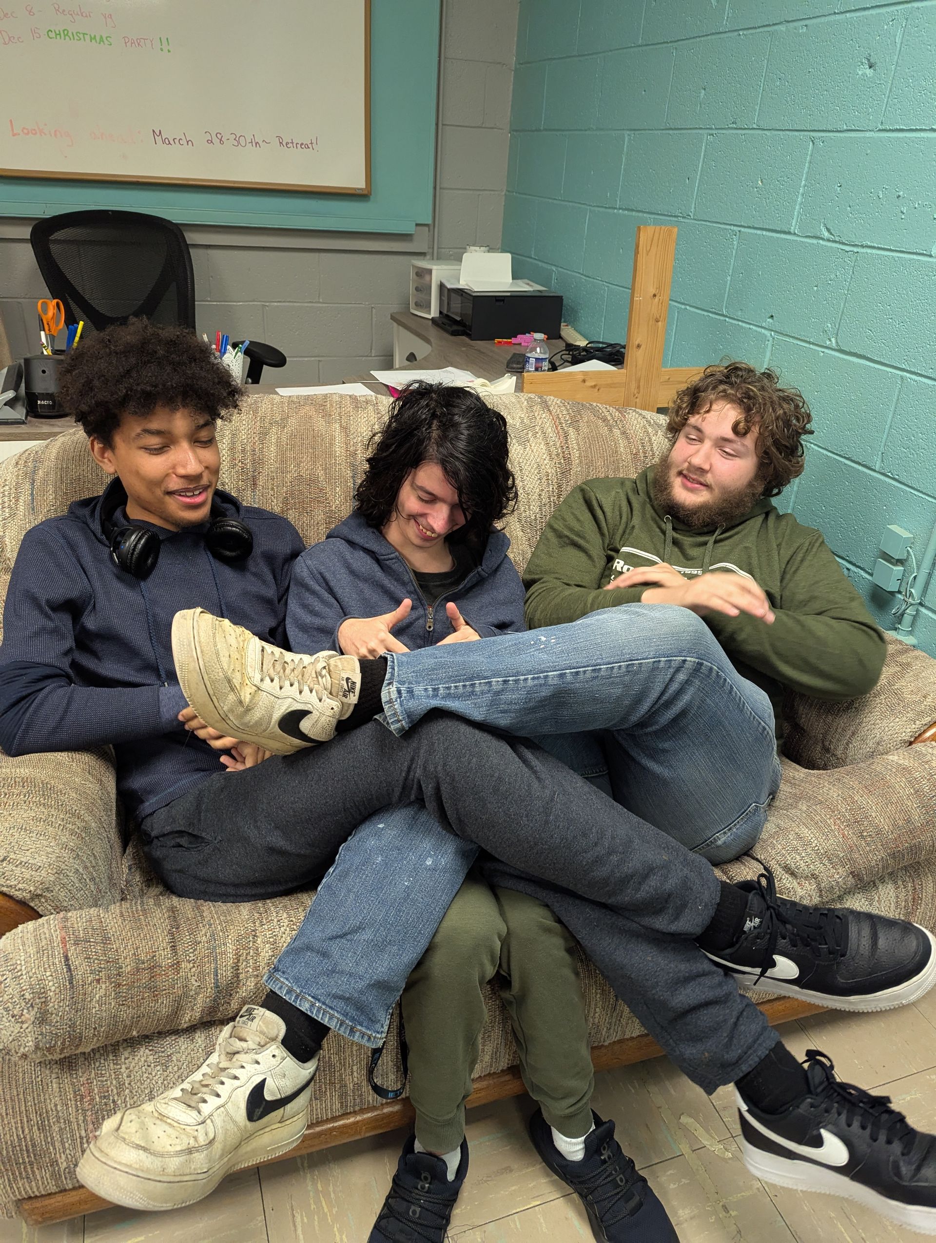Three young people seated on a sofa, laughing and sharing a moment.