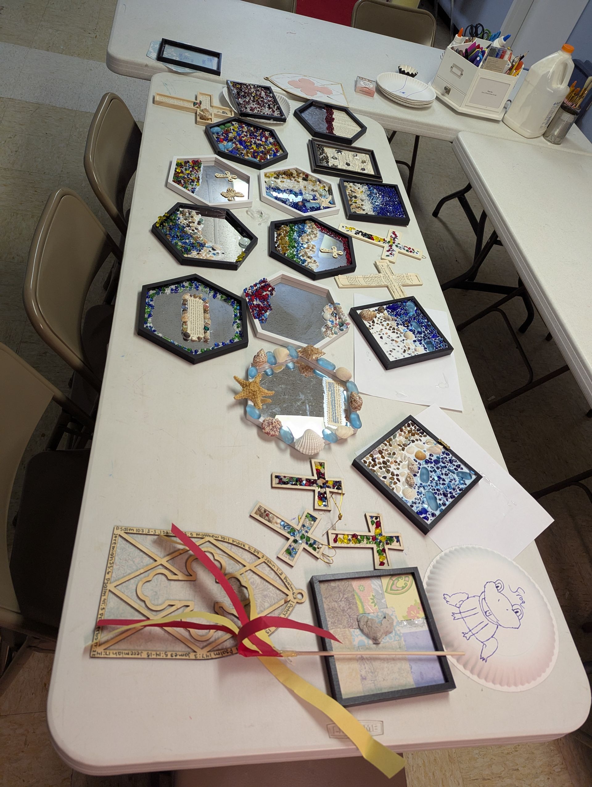 Table with various decorated mirrors and craft supplies.
