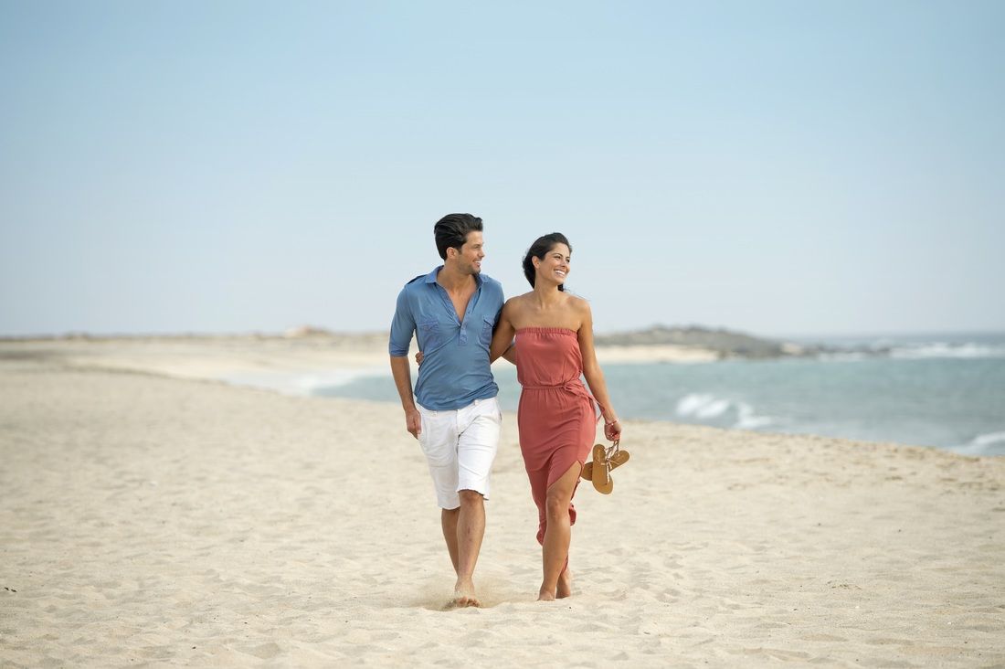 A man and a woman are walking on the beach.