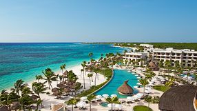 riviera maya resort An aerial view of a beach resort with a large pool and palm trees.