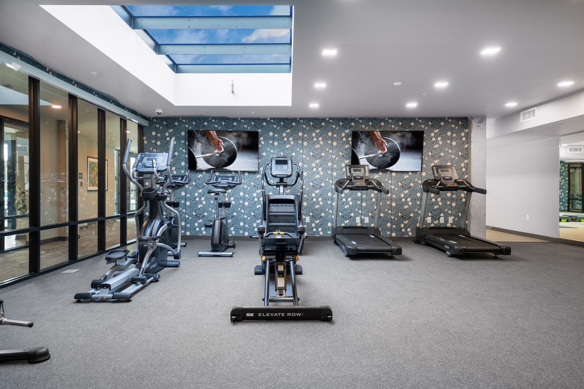 A gym with a lot of exercise equipment and a skylight