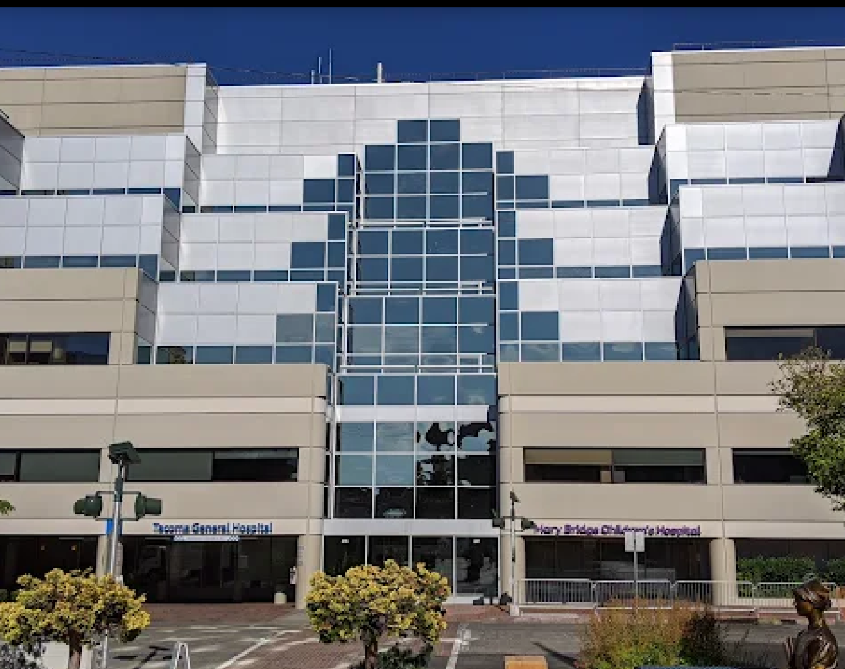 A large apartment building with a lot of windows and cars parked in front of it.