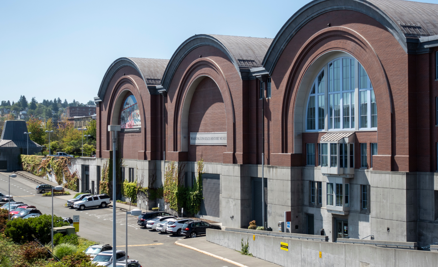 Brick building with arched windows, Seattle. Cars parked on the street. Bright day.