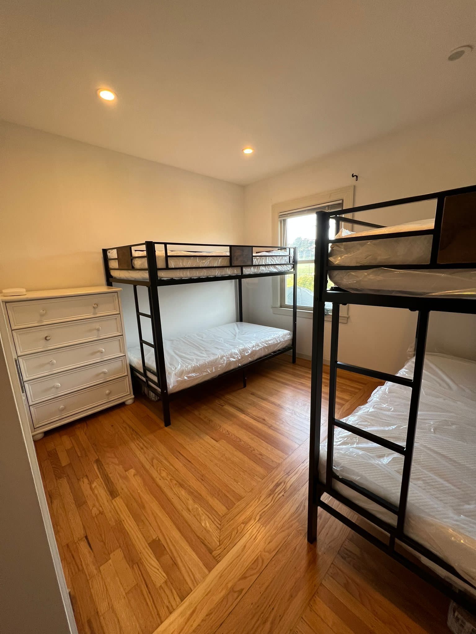 A bedroom with two bunk beds and a dresser.
