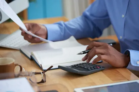 Hands using calculator and papers at a desk in an office
