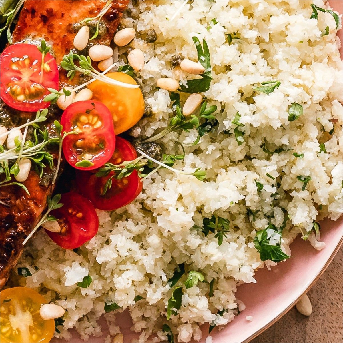 Plato de salmón con arroz de coliflor, tomates, alcaparras y hierbas.