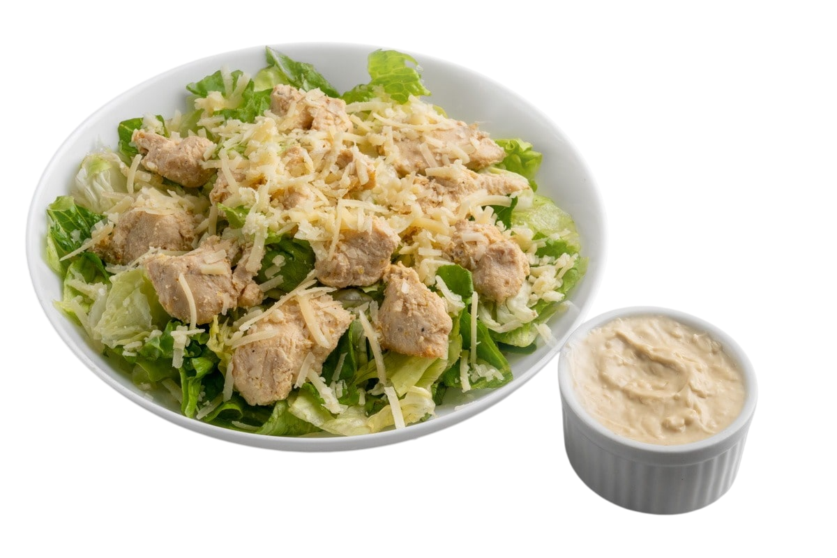 Ensalada César de pollo con aderezo cremoso en un bol blanco.