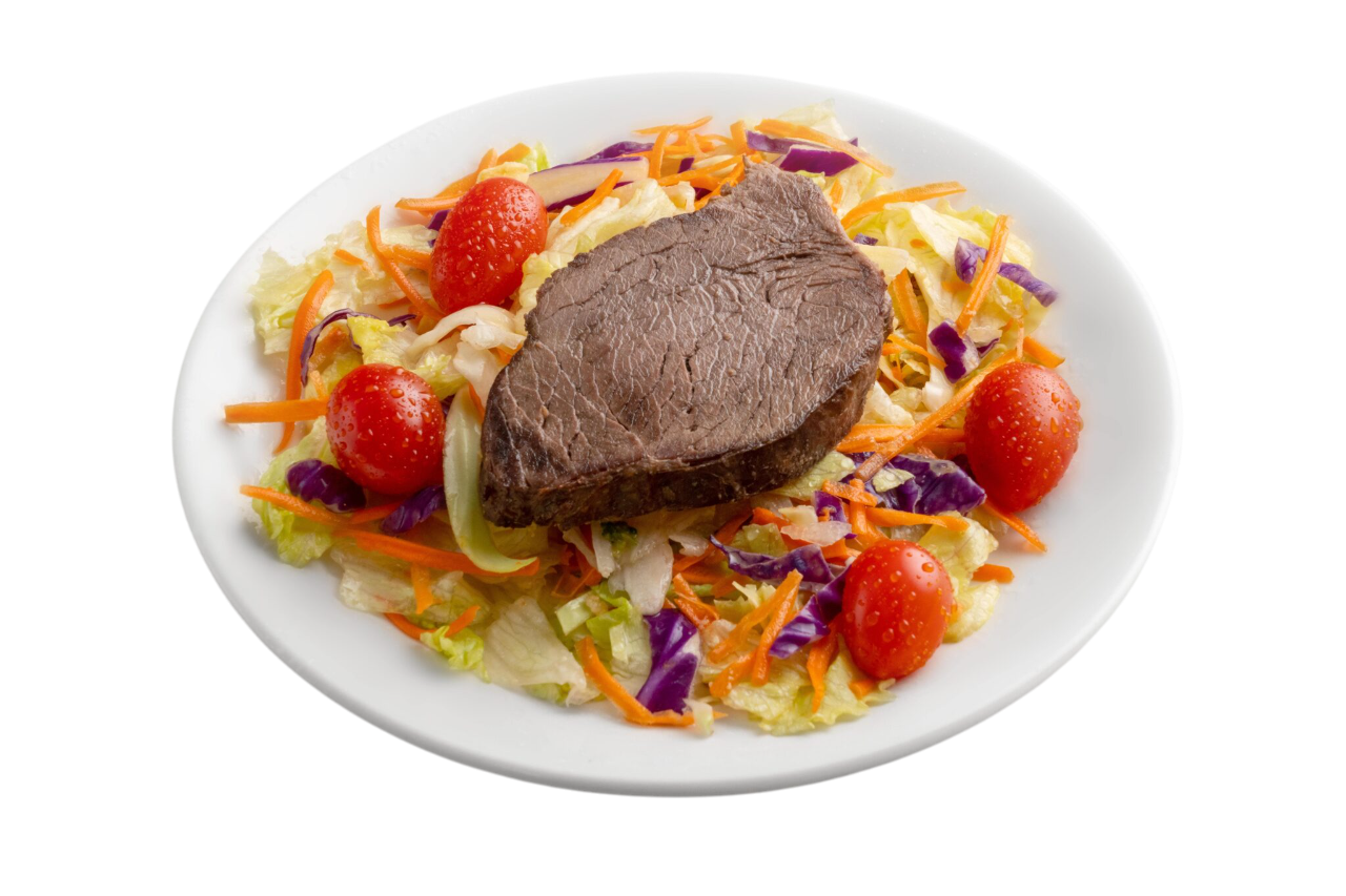 Filete sobre una cama de repollo rallado, zanahorias y tomates en un plato blanco.