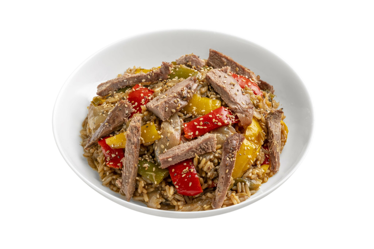 Salteado de ternera y verduras servido en un bol blanco. Incluye ternera en rodajas, pimientos rojos