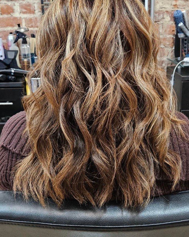 A woman is sitting in a chair with her hair in a salon.