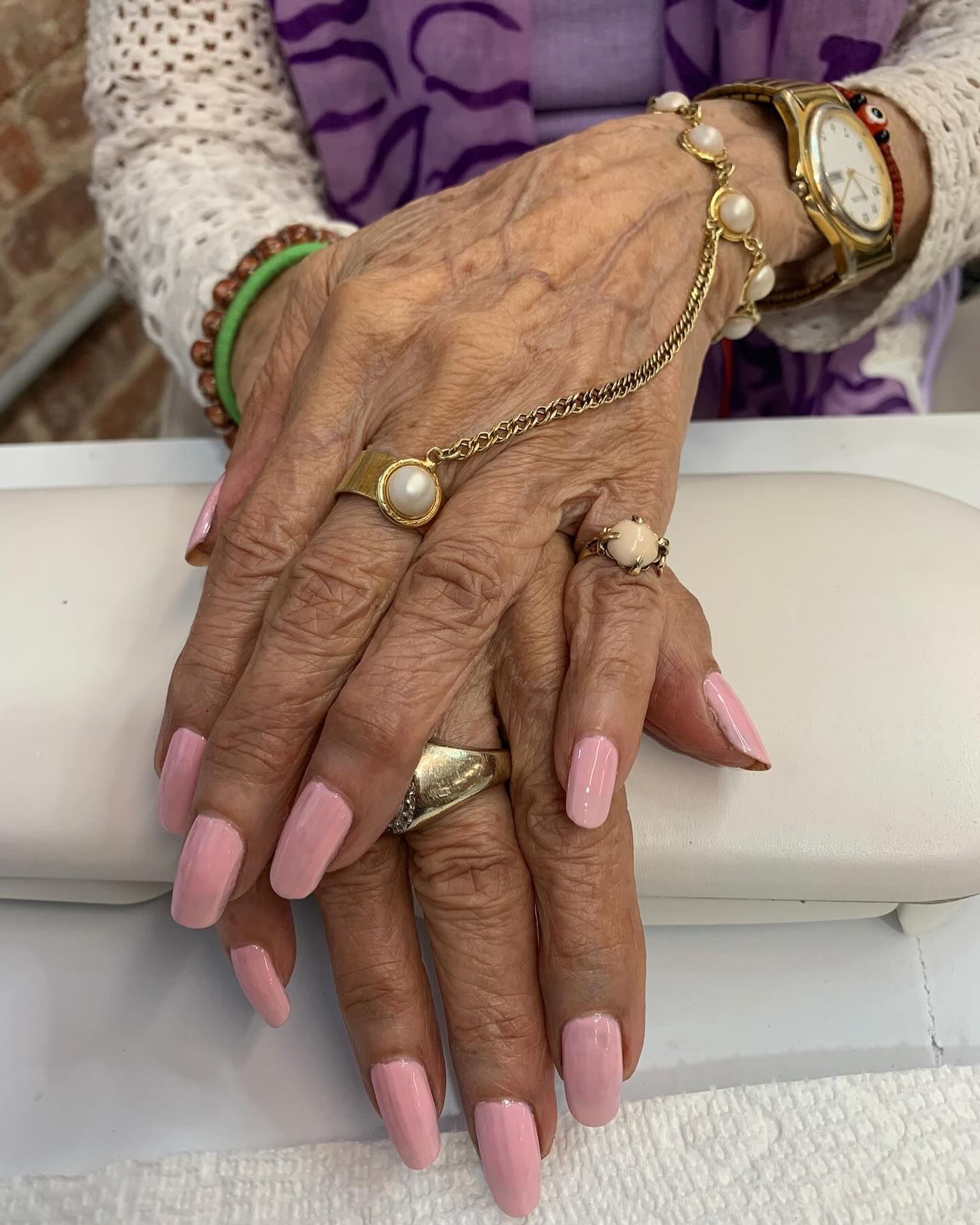 A close up of a woman 's hands with pink nails and rings.
