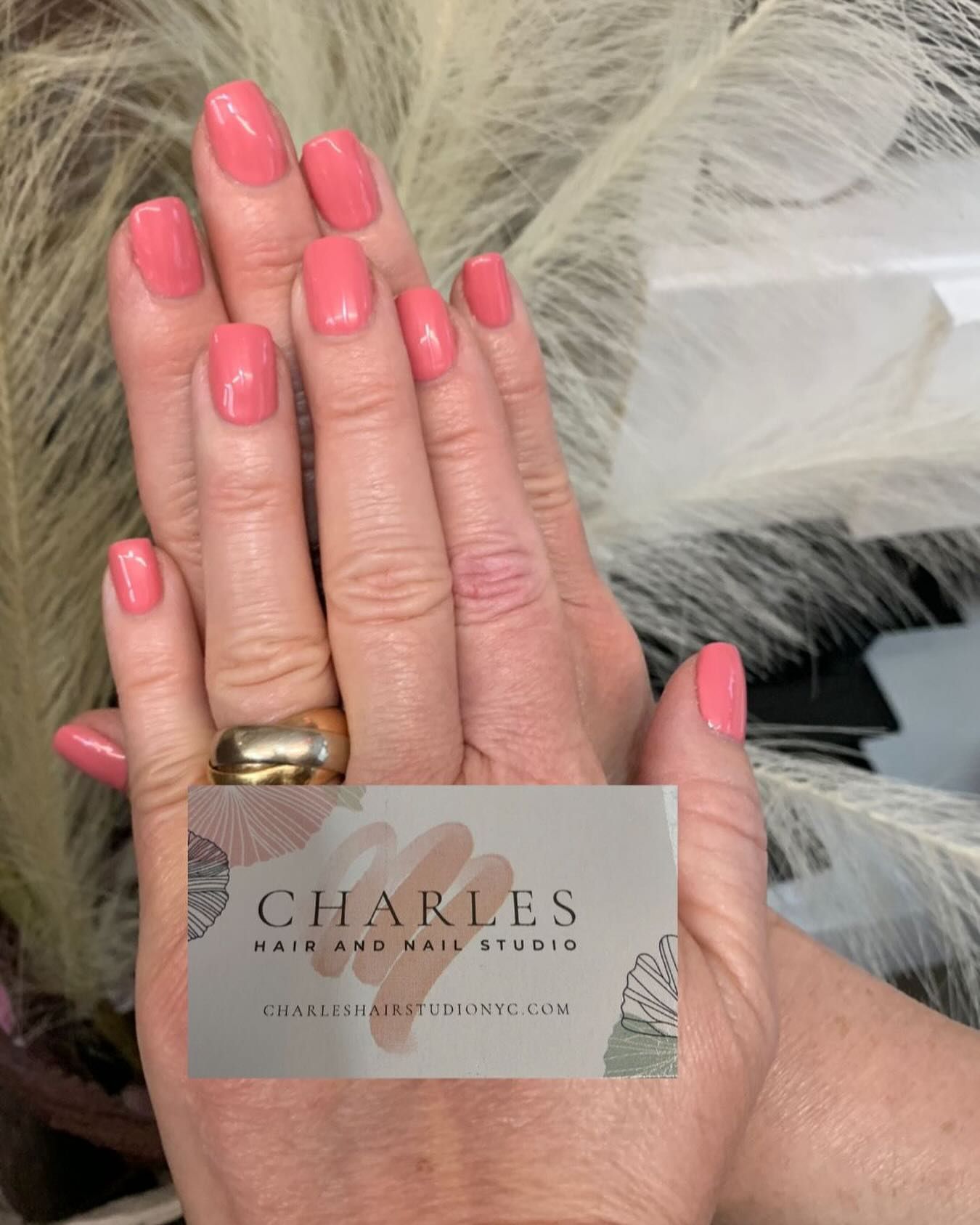 A woman is holding a business card for charles hair and nail studio