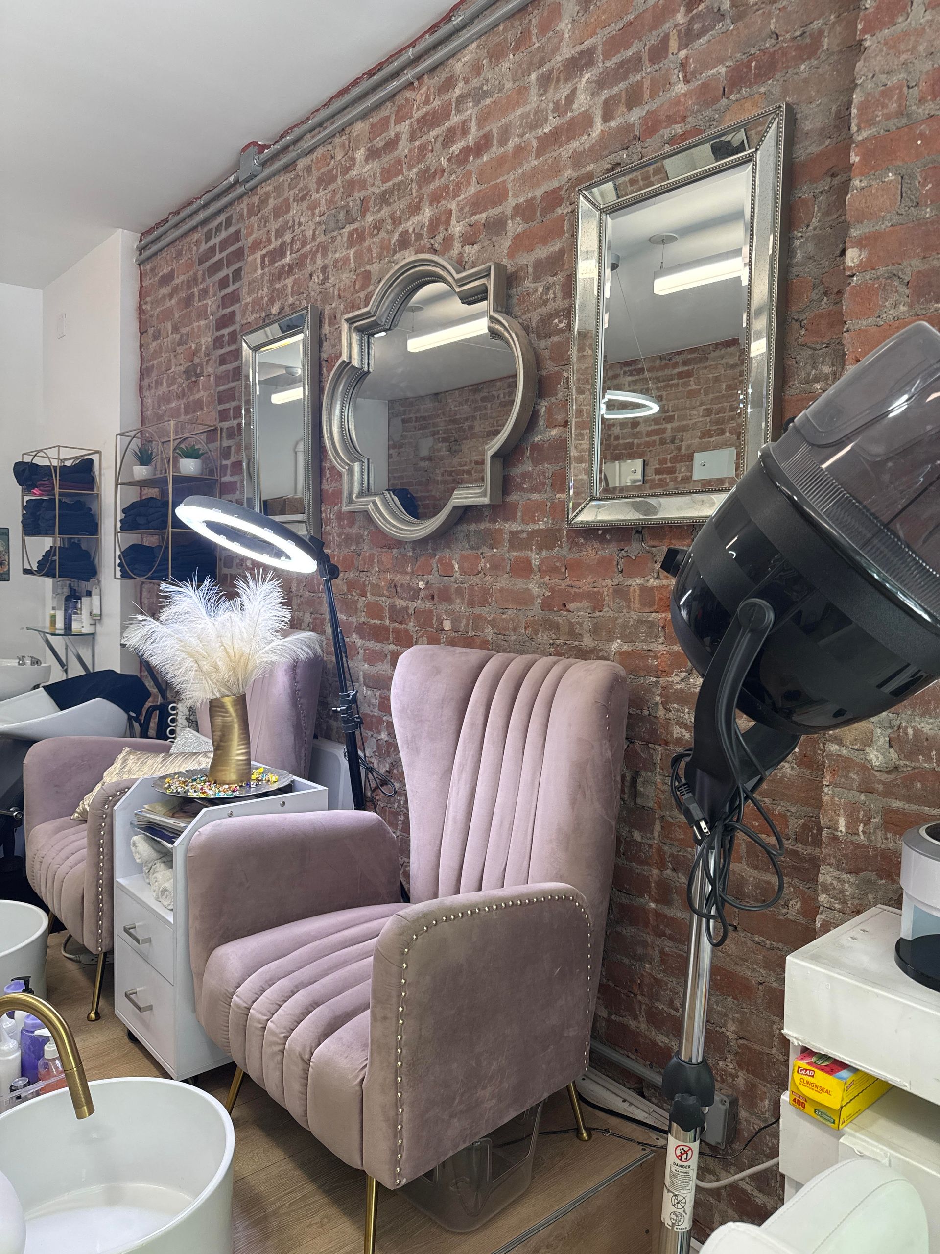 A room with a brick wall , chairs , mirrors and a hair dryer.