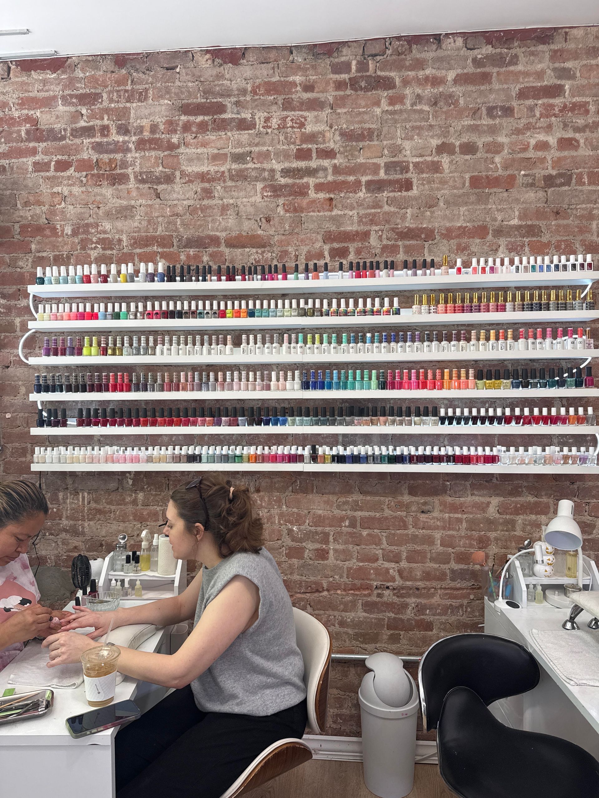 Two women are getting their nails done in a nail salon.