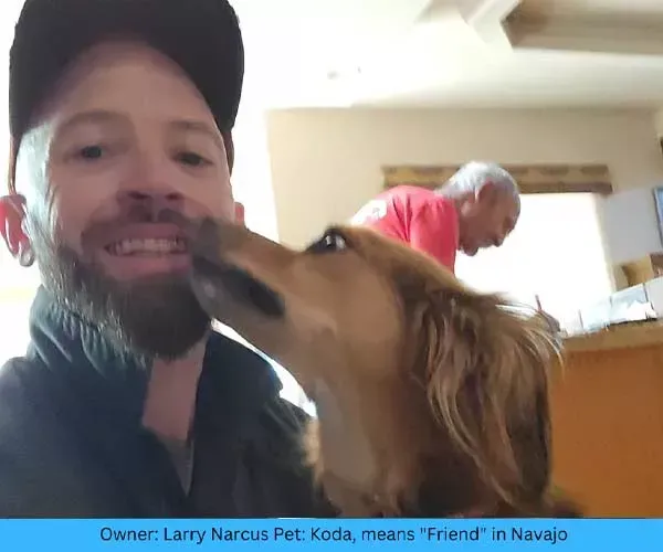Man smiles as dog licks his face. An older person is in the background. Caption: Owner Larry Narcus Pet: Koda.