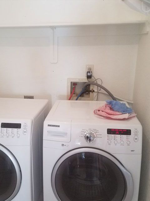 Laundry room: Washer and dryer against white wall, with a utility panel and an outlet.