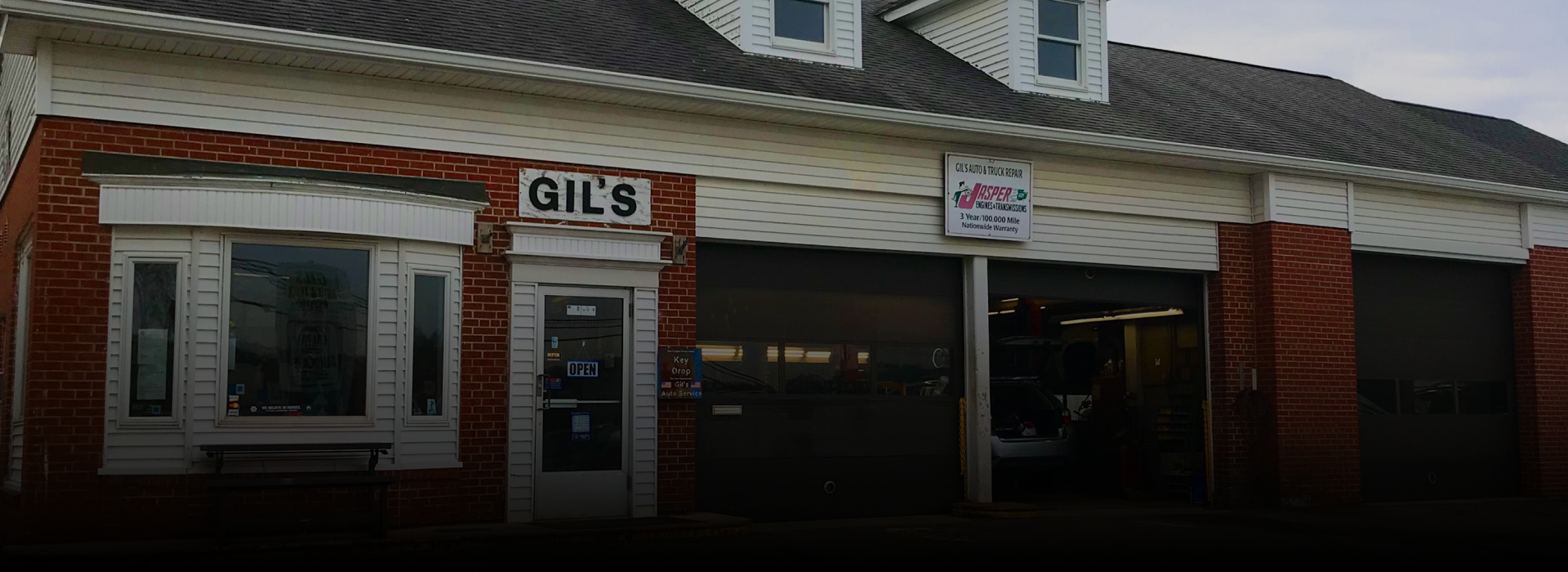 Exterior of a brick auto repair shop with an open garage bay and “GILES” sign over the door | Gil's Auto & Truck Repair