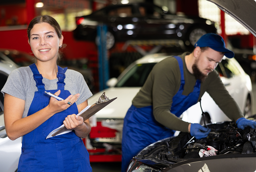 Auto shop workers inspecting a car; one holds a clipboard while another works under the hood. | Gil's Auto & Truck Repair