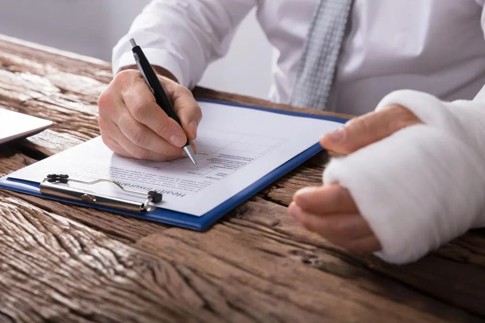 Person With Bandaged Wrist Writing on a Clipboard — SSP Insurance In Yeppoon, QLD