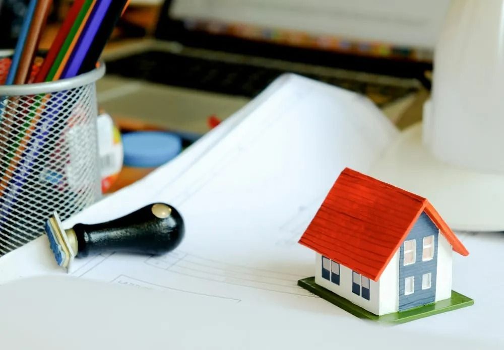 Miniature House on Papers With a Stamp, Pencils, and Computer — SSP Insurance In Yeppoon, QLD