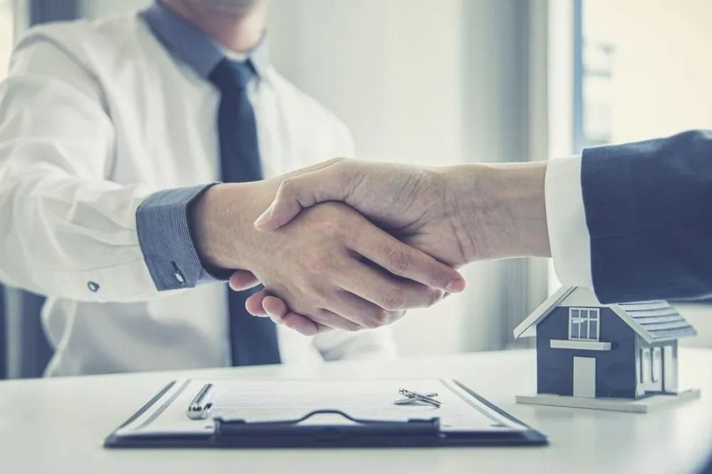 Two People Shaking Hands Over a Small House Model — SSP Insurance In Rockhampton, QLD