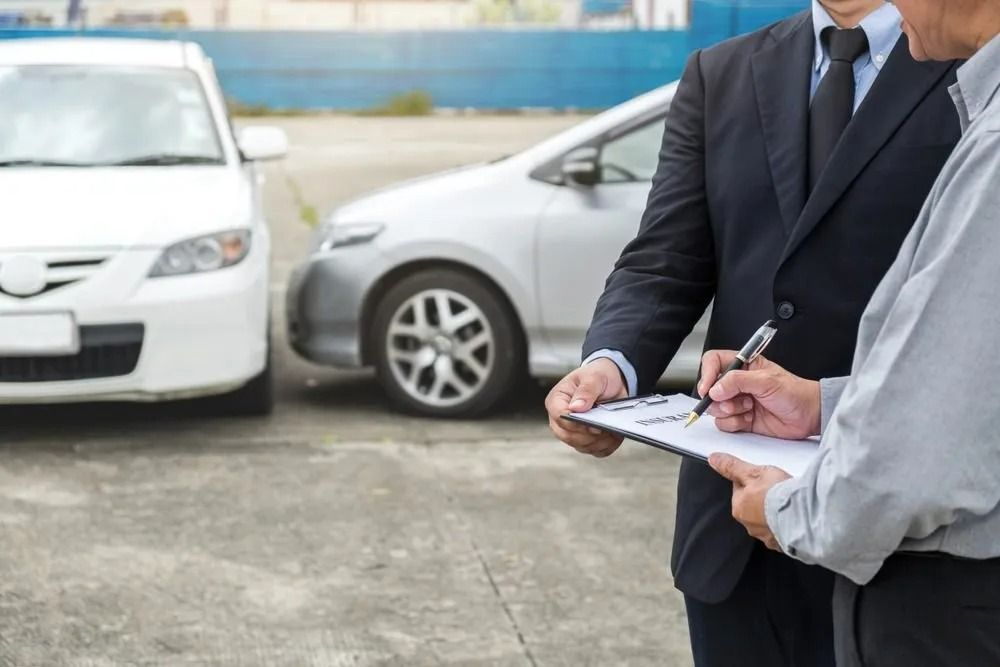 Two Men in Suits, Writing on a Clipboard Next to Two Cars — SSP Insurance In Rockhampton, QLD