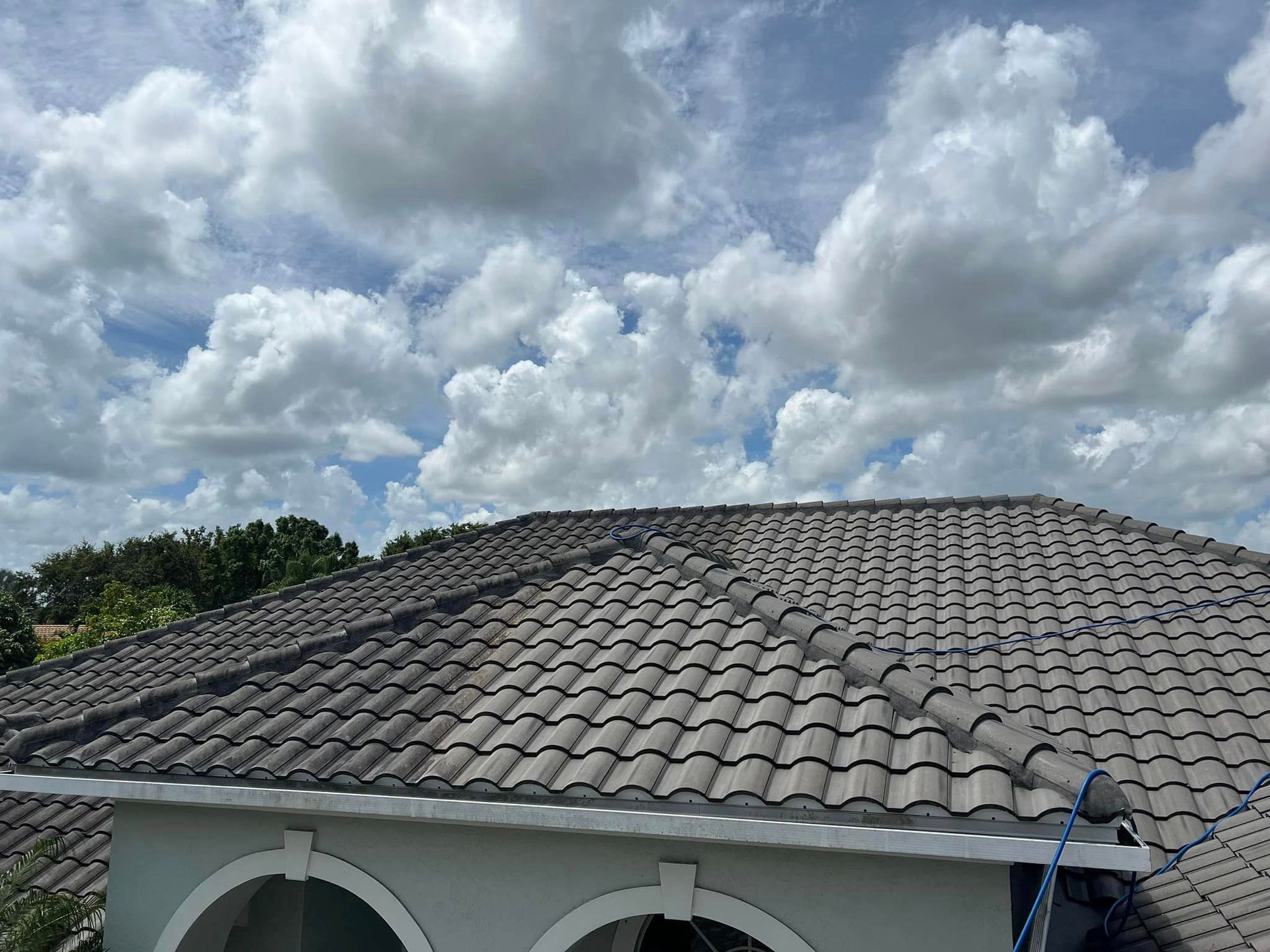 A roof of a house with a blue sky and clouds in the background.