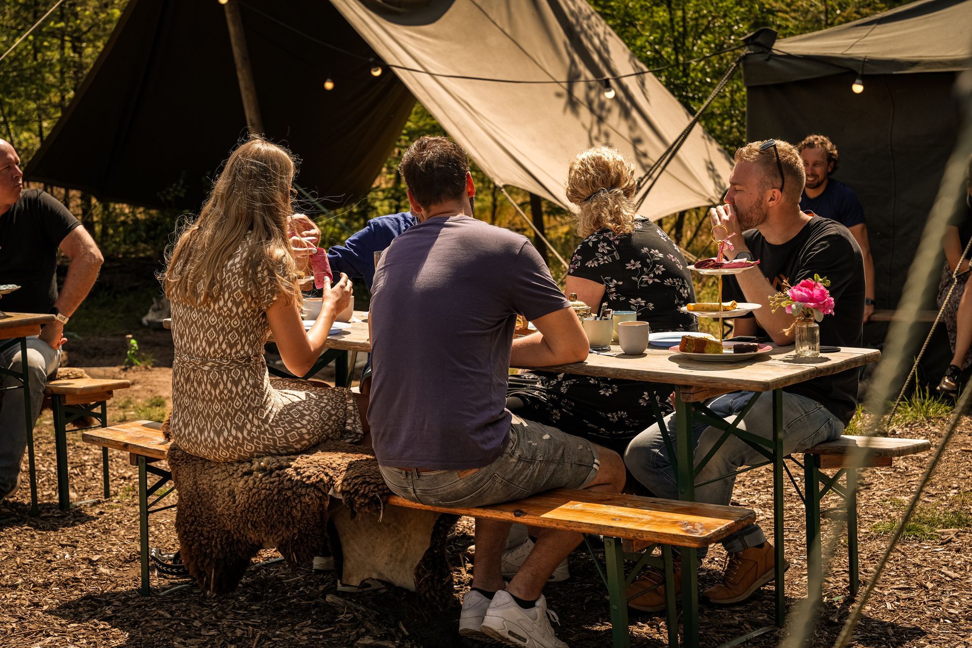 Een groep mensen zit aan high tea in de bossen