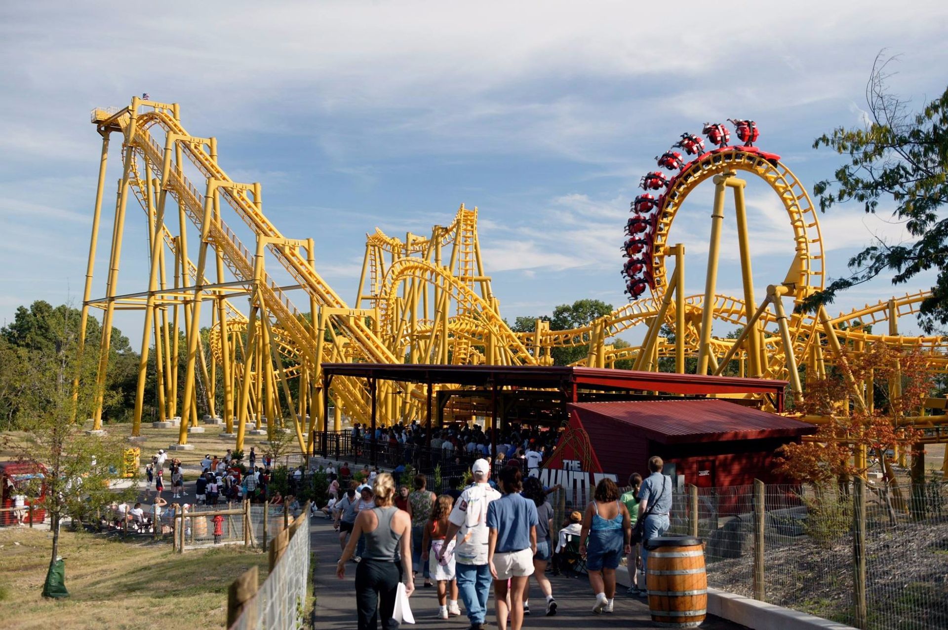 People walking in front of a roller coaster at an amusement park