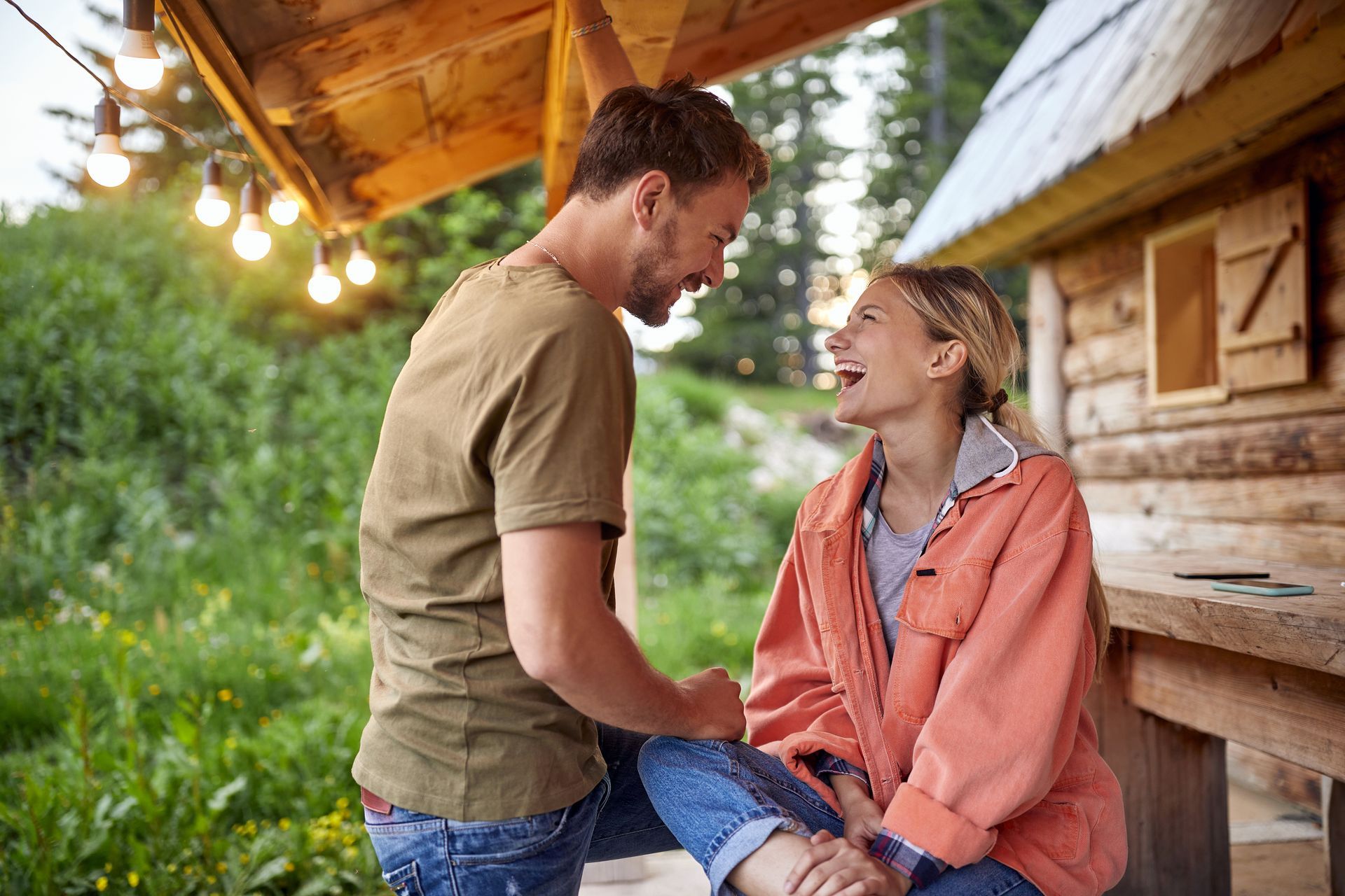 A man and a woman are sitting under a wooden roof holding hands.