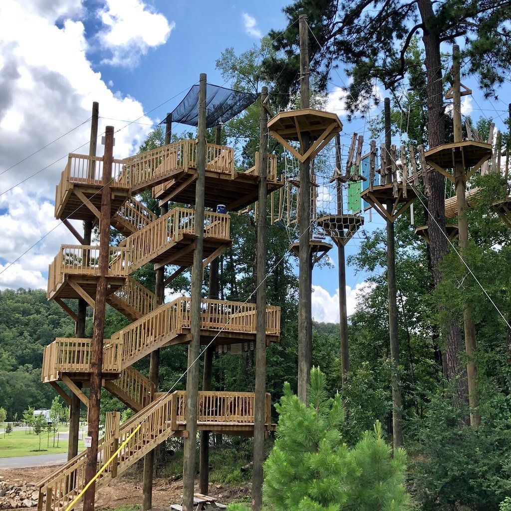 A wooden tower with stairs leading up to it is surrounded by trees.