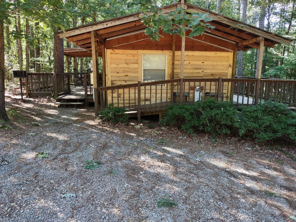 A small wooden cabin with a porch in the woods.