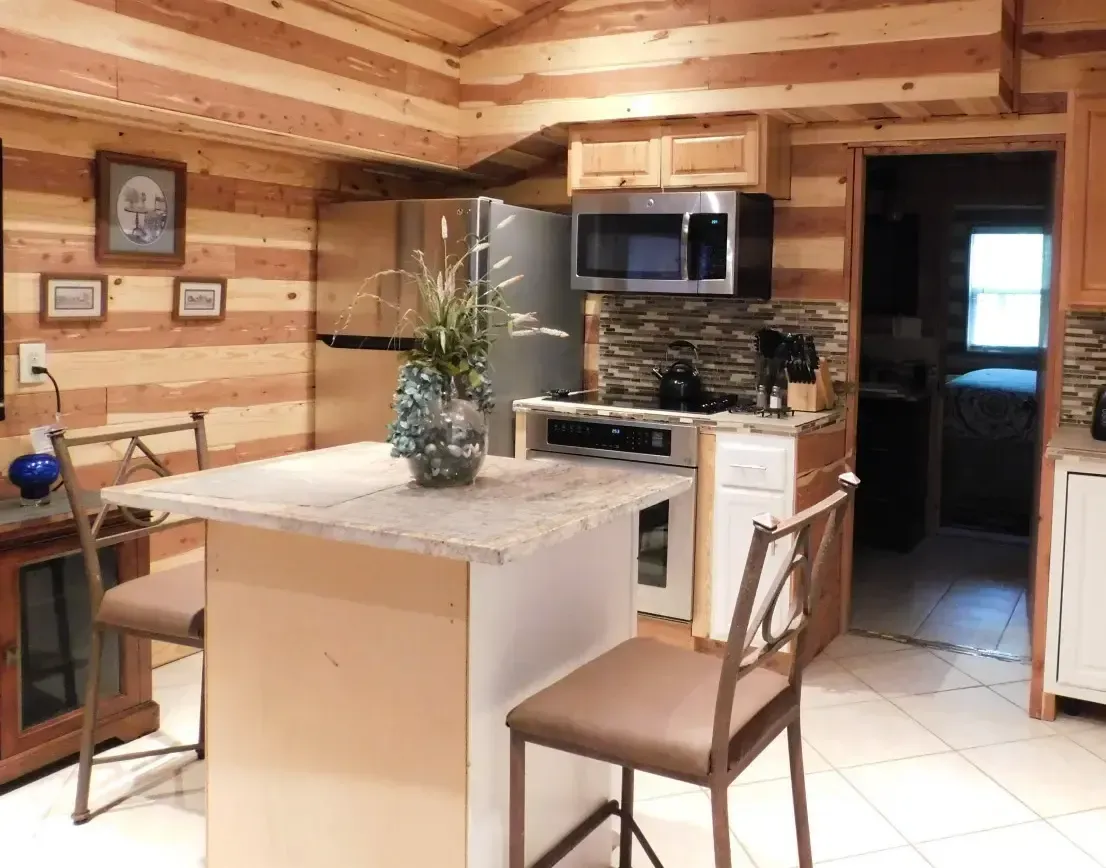 A kitchen in a log cabin with a large island in the middle.