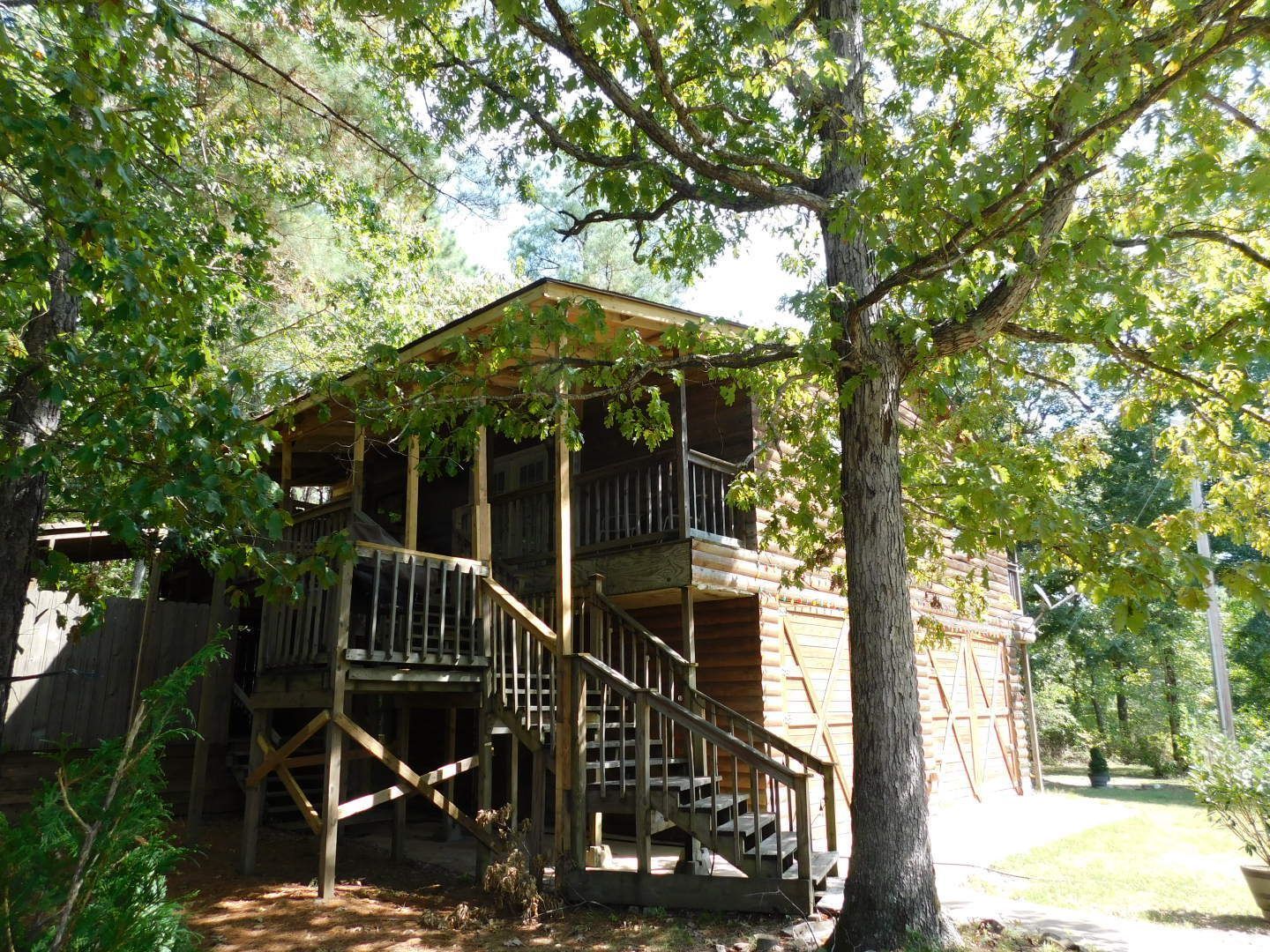 A wooden house with stairs leading up to it is surrounded by trees.