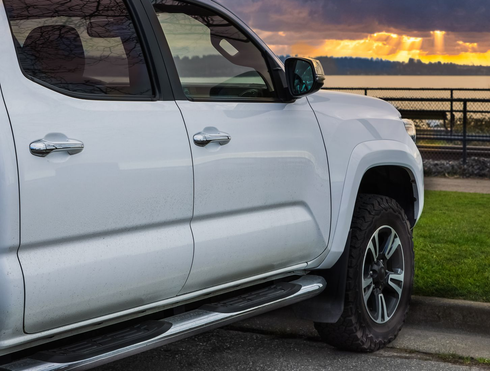 White pickup truck parked by a curb at sunset near water and a railing White pickup truck parked by a curb at sunset near water and a railing